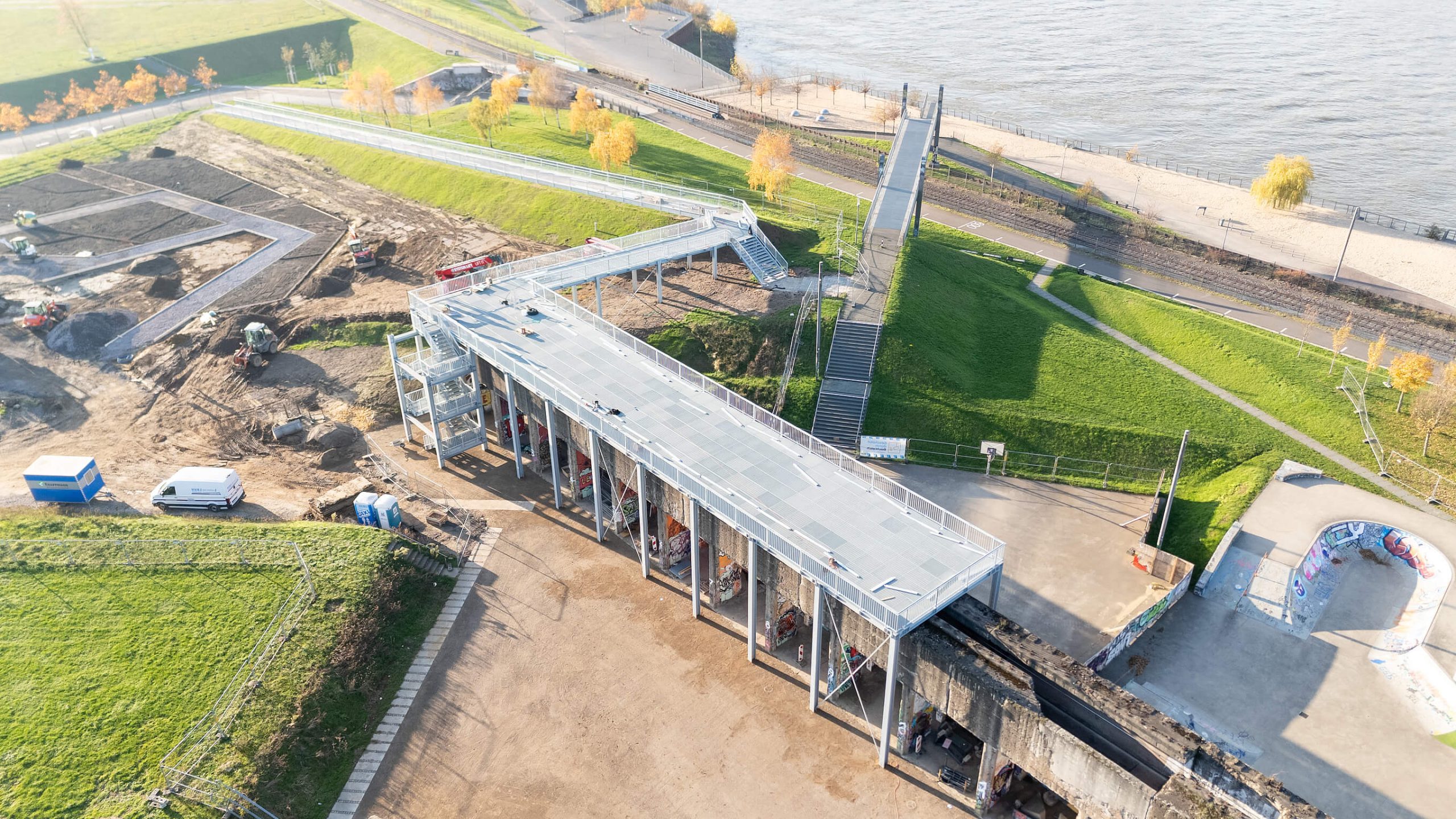Luftaufnahme des Skywalks im Bau: winkelförmige Stahlplattform auf der Erzbunkerwand mit Treppenturm, daneben Baumaschinen.
